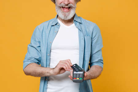 Cropped image elderly gray-haired mustache bearded man in blue shirt isolated on yellow background.の写真素材