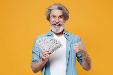Funny elderly gray-haired mustache bearded man in blue shirt isolated on yellow background.の写真素材