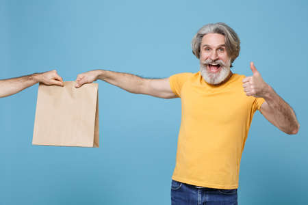 Excited elderly gray-haired mustache bearded man in yellow t-shirt isolated on blue background.