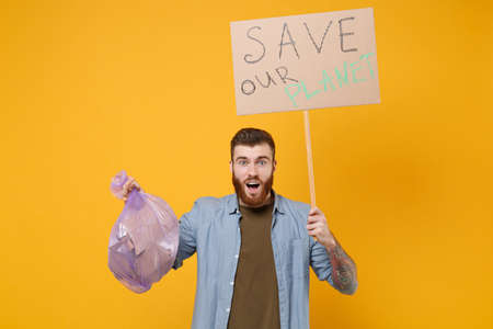 Shocked young protesting man guy hold in hand protest sign broadsheet placard on stick trash bag...