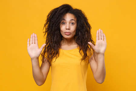 Shocked young african american woman girl in casual t-shirt posing isolated on yellow orange...