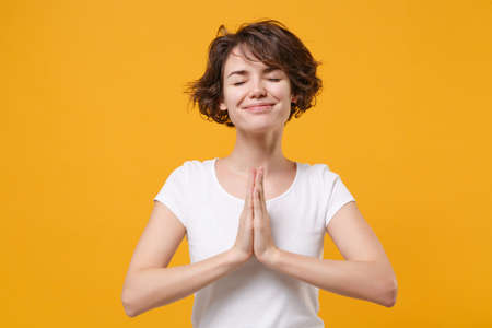 Smiling young brunette woman girl in white t-shirt posing isolated on yellow orange wall background....