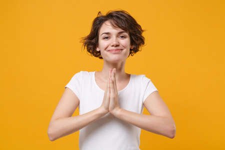 Smiling young brunette woman girl in white t-shirt posing isolated on yellow orange background...