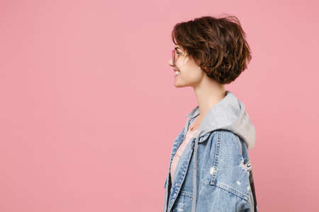 Side view of smiling young brunette woman girl in casual denim jacket eyeglasses posing isolated on...