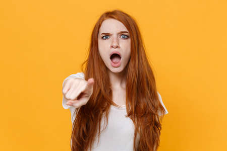 Shocked young redhead woman girl in white blank empty t-shirt posing isolated on yellow background....