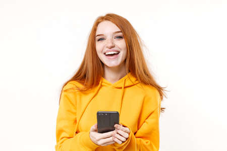 Laughing young redhead woman girl in yellow hoodie posing isolated on white background studio...