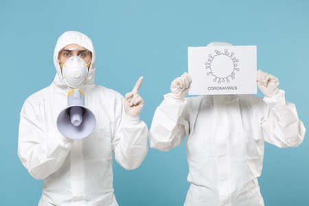 People in protective suits respirator masks scream in megaphone isolated on blue background studio. Epidemic pandemic new rapidly spreading coronavirus 2019-ncov medicine flu virus conceptの写真素材