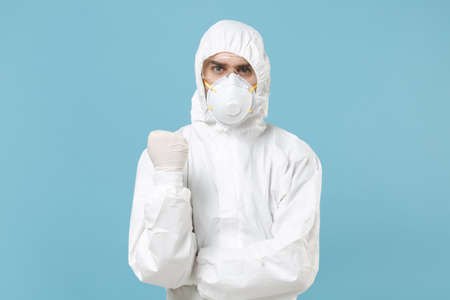 Man in white protective suit respirator mask isolated on blue background studio.の写真素材