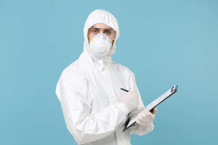 Man in white protective suit respirator mask hold clipboard with paper document isolated on blue...