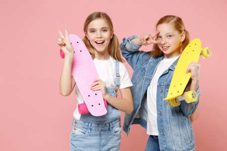 Excited little kids girls 12-13 years old in white t-shirt, denim clothes isolated on pastel pink...