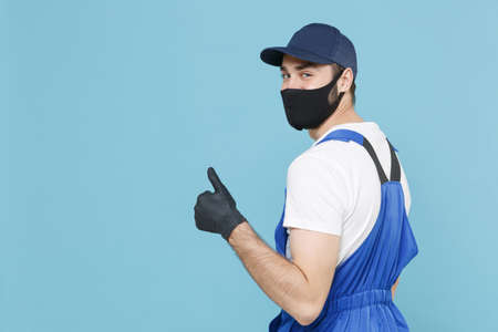 Delivery man in cap t-shirt coveralls uniform sterile face mask gloves isolated on blue background studio. Guy employee courier Service quarantine pandemic coronavirus virus covid-19 2019-ncov conceptの写真素材