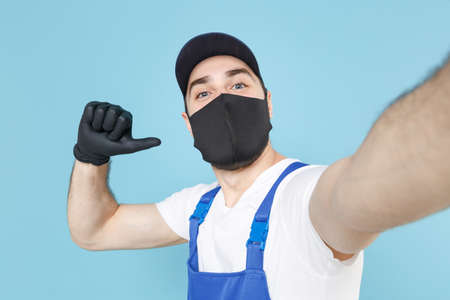 Delivery man in cap t-shirt coveralls uniform sterile face mask gloves isolated on blue background...