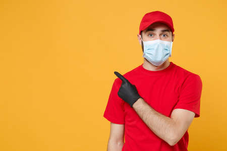 Delivery man in red cap blank t-shirt uniform sterile face mask gloves isolated on yellow background...