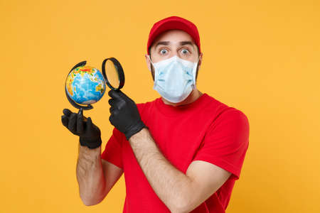 Delivery man in red cap blank t-shirt uniform sterile face mask gloves isolated on yellow background studio Guy employee working courier Service quarantine pandemic coronavirus virus 2019-ncov conceptの写真素材