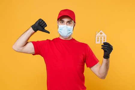 Delivery man in red cap blank t-shirt uniform sterile face mask gloves isolated on yellow background studio Guy employee working courier Service quarantine pandemic coronavirus virus 2019-ncov conceptの写真素材