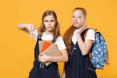 Girls 12-13 years old in white t-shirt blue school uniform dresses hold schoolbooks isolated on yellow background children studio portrait Childhood kids education lifestyle concept Mock up copy spaceの写真素材