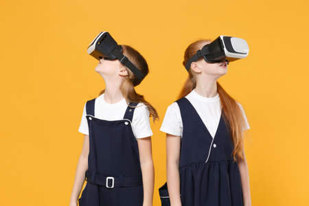 Two girls 12-13 years old in headset virtual vr reality t-shirt blue school uniform isolated on...