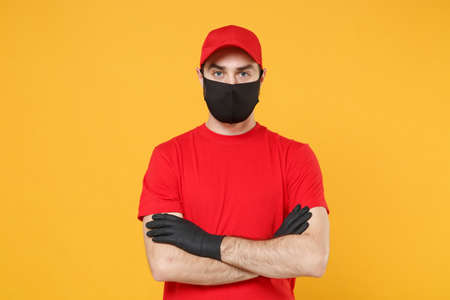 Delivery man in red cap blank t-shirt uniform sterile face mask gloves isolated on yellow background studio Guy employee working courier Service quarantine pandemic coronavirus virus 2019-ncov conceptの写真素材