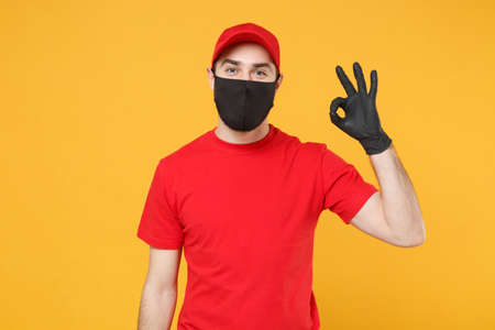 Delivery man in red cap blank t-shirt uniform sterile face mask gloves isolated on yellow background studio Guy employee working courier Service quarantine pandemic coronavirus virus 2019-ncov conceptの写真素材