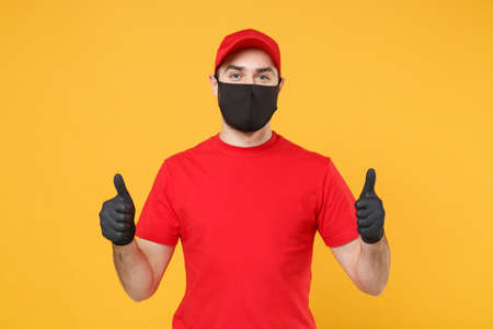 Delivery man in red cap blank t-shirt uniform sterile face mask gloves isolated on yellow background studio Guy employee working courier Service quarantine pandemic coronavirus virus 2019-ncov conceptの写真素材