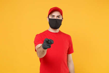 Delivery man in red cap blank t-shirt uniform sterile face mask gloves isolated on yellow background studio Guy employee working courier Service quarantine pandemic coronavirus virus 2019-ncov conceptの写真素材