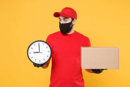 Delivery man employee in red cap blank t-shirt uniform face mask glove hold empty cardboard box isolated on yellow background studio Service quarantine pandemic coronavirus flu virus 2019-ncov conceptの写真素材