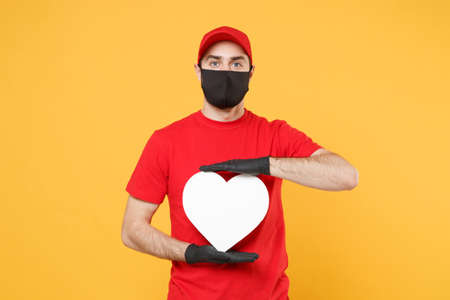 Delivery man in red cap blank t-shirt uniform sterile face mask gloves isolated on yellow background studio Guy employee working courier Service quarantine pandemic coronavirus virus 2019-ncov conceptの写真素材