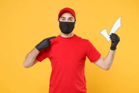 Delivery man in red cap blank t-shirt uniform sterile face mask gloves isolated on yellow background studio Guy employee working courier Service quarantine pandemic coronavirus virus 2019-ncov conceptの写真素材