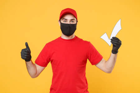 Delivery man in red cap blank t-shirt uniform sterile face mask gloves isolated on yellow background studio Guy employee working courier Service quarantine pandemic coronavirus virus 2019-ncov conceptの写真素材