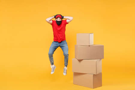 Delivery man employee in red cap blank t-shirt uniform face mask glove hold empty cardboard box isolated on yellow background studio Service quarantine pandemic coronavirus flu virus 2019-ncov conceptの写真素材