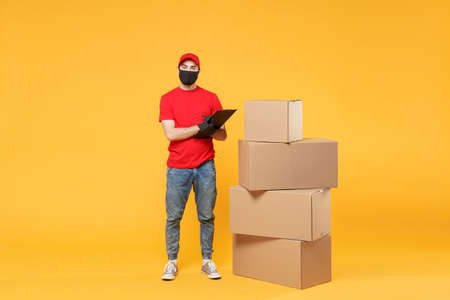 Delivery man employee in red cap blank t-shirt uniform face mask glove hold empty cardboard box isolated on yellow background studio Service quarantine pandemic coronavirus flu virus 2019-ncov conceptの写真素材