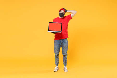 Delivery man in red cap blank t-shirt uniform mask gloves isolated on yellow background studio Guy...