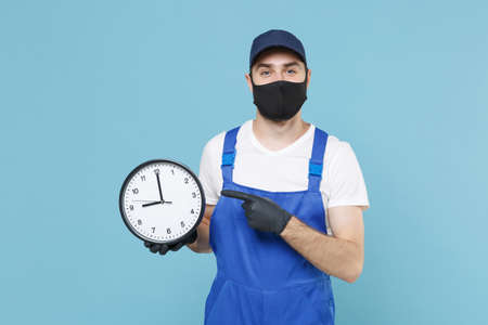 Delivery man in cap t-shirt uniform sterile face mask gloves isolated on blue background studio Guy...