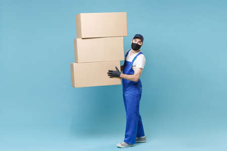Full length delivery man in cap t-shirt uniform sterile face mask gloves isolated on blue background...