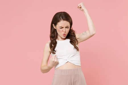 Happy young brunette woman girl in light casual clothes posing isolated on pastel pink wall background studio portrait. People emotions lifestyle concept. Mock up copy space. Doing winner gesture.の写真素材