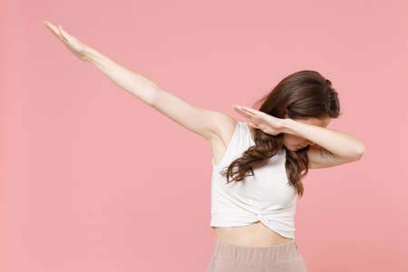 Young brunette woman girl in light casual clothes posing isolated on pastel pink background studio portrait. People sincere emotions lifestyle concept. Mock up copy space. Showing DAB dance gesture.の写真素材