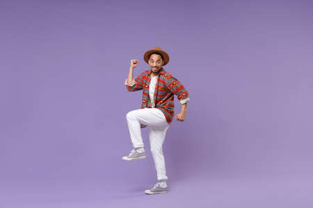Excited young african american guy in casual colorful shirt hat posing isolated on violet wall background studio portrait. People emotions lifestyle concept. Mock up copy space. Doing winner gesture.の写真素材