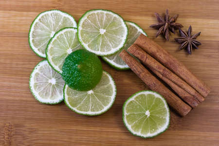 Green lime slices with cinnamon sticks on a bamboo board