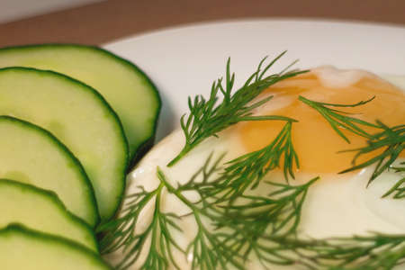 Fried egg serving slices of cucumber