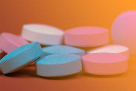 Round vitamin tablets of different colors close-up