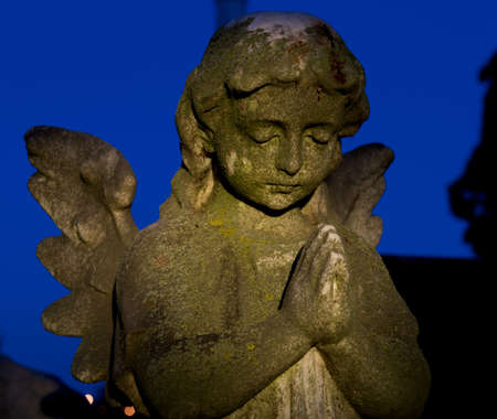 Cemetery headstone of a winged child angel or cherub with hand folded in prayer.の写真素材