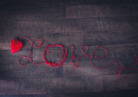 Red clews in shape of heart and text love on wooden back