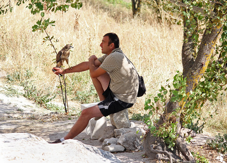 Ukraine, Bakhchisaray - September 06, 2011: Man and tame bird of prey on the trail in Calais