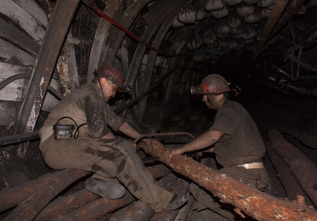 Donetsk, Ukraine - August, 16, 2013: Miners sawn timber for the construction of roof support in...