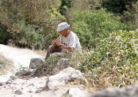 Ukraine, Bakhchisaray - September 06, 2011: A man playing on a pipe sitting on the tourist trail. Crimeaのeditorial素材