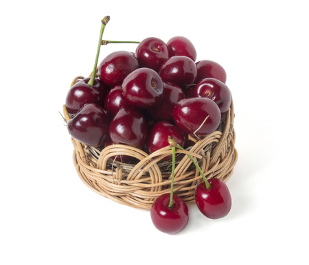 Ripe cherry in a wicker basket. Isolated on white backgroundの写真素材