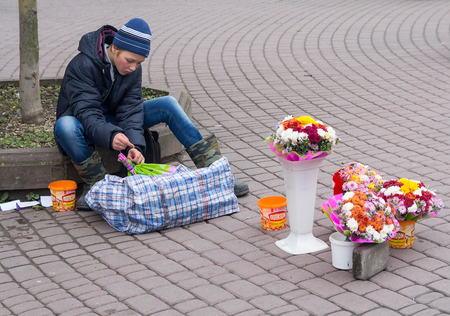Ivano-Frankivsk, Ukraine - October 17, 2015: Teenager sells flowers sitting on the sidewalk on the main streetのeditorial素材