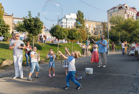 Kiev, Ukraine - Sepnember 19, 2015: Man entertains children running large bubbles in the playgroundのeditorial素材