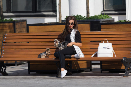 Kiev, Ukraine - September 18, 2015: Lady with two Yorkshire terrier resting on a bench in the park