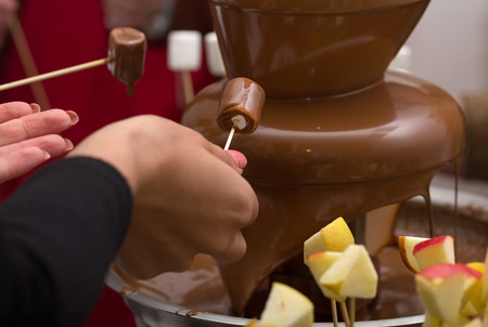 Chocolate fountain and extends a hand to it. Foodの写真素材